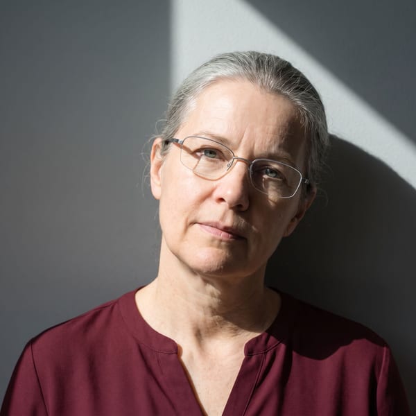 Woman with her head tilted and a hard shadow falling across the wall behind her